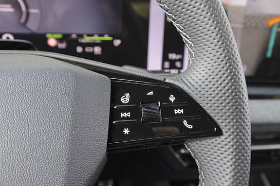 Detailaufnahme des Multifunktionslenkrads eines Audi Q6 SUV e-tron quattro mit Bedientasten für Heizung, Telefon, Sprachsteuerung und Mediensteuerung.