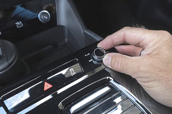Detailaufnahme des Bedienfelds im Innenraum eines Audi Q6 SUV e-tron quattro mit Hand am Drehregler.