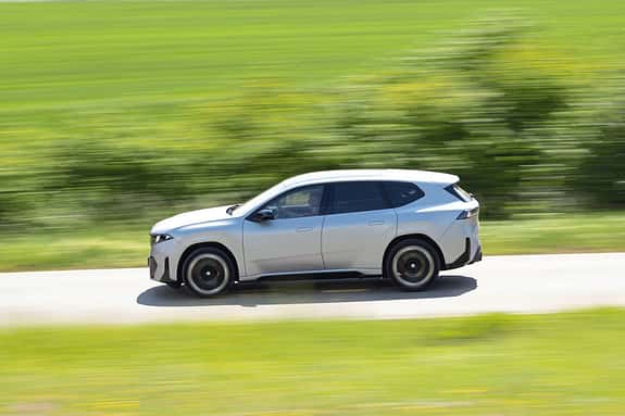 BMW IS 30x drive SUV fährt auf einer Landstraße, Seitenansicht, dynamische Bewegungsunschärfe, grüne Landschaft.