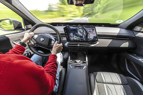 Innenraumaufnahme eines BMW IS 30x drive mit Fokus auf das Cockpit, Lenkrad und das zentrale Infotainmentsystem während der Fahrt.