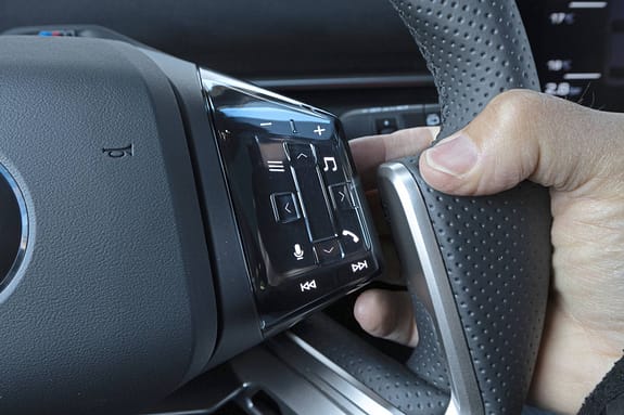 Detailaufnahme des Multifunktionslenkrads eines BMW IS 30x drive mit beleuchteten Bedientasten und Daumensteuerung.