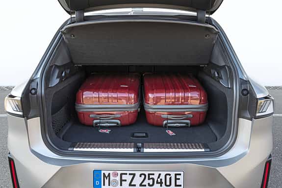 Der Kofferraum eines BMW IS 30x drive mit zwei roten Hartschalenkoffern, fotografiert von hinten bei geöffneter Heckklappe.