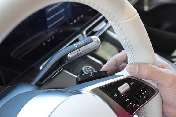 Detailaufnahme des Lenkrads und des Schalthebels eines Mercedes GLC 400 4matic EQ. Zu sehen sind Schaltwippen, Bedienelemente und der elektronische Wählhebel.