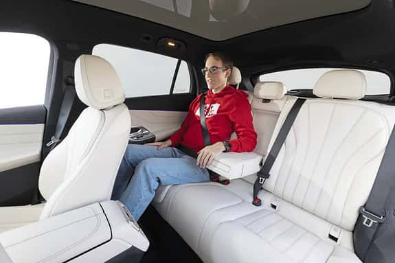 Innenraumaufnahme eines Mercedes GLC 400 4matic EQ mit einer Person auf der Rückbank, helle Lederausstattung.