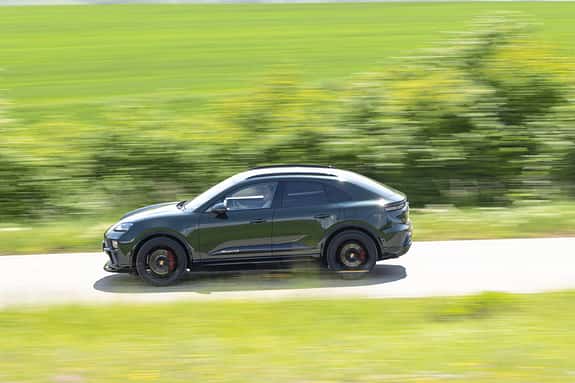 Porsche Macan 4S fährt auf einer Landstraße, Seitenansicht, grüne Landschaft im Hintergrund, Bewegungsunschärfe.