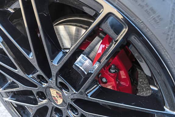 Detailaufnahme einer schwarzen Leichtmetallfelge mit Porsche-Logo und rotem Bremssattel des Porsche Macan 4S.