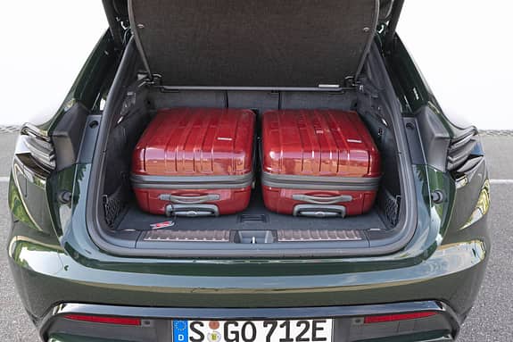 Der geöffnete Kofferraum eines Porsche Macan 4S mit zwei roten Hartschalenkoffern.