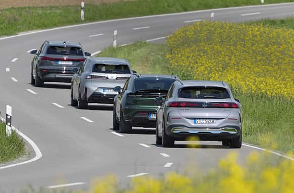Vier aktuelle Elektro-SUVs (BMW i5 30xDrive, Mercedes GLC 400 4MATIC EQ, Audi Q6 SUV e-tron quattro, Porsche Macan 4S) fahren auf einer Landstraße im Konvoi.