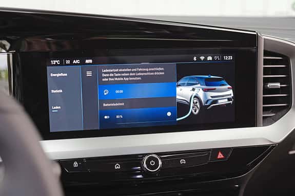 Das Bild zeigt das zentrale Infotainment-Display eines Opel Mokka, das den Ladevorgang eines Elektrofahrzeugs anzeigt. Zu sehen sind Ladeeinstellungen, Batterieladelimit und eine Grafik des Fahrzeugs beim Laden.