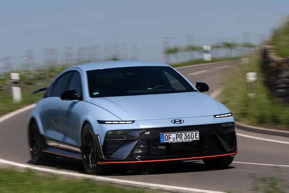 Hyundai Ioniq 6N AWD auf Landstraße in Kurvenfahrt, Frontansicht, sportliches Elektroauto.