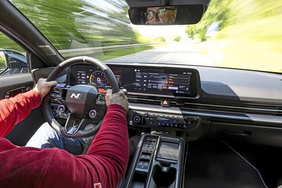 Innenaufnahme eines Hyundai Ioniq 6N AWD während der Fahrt, Fokus auf Cockpit, Lenkrad und Fahrer.