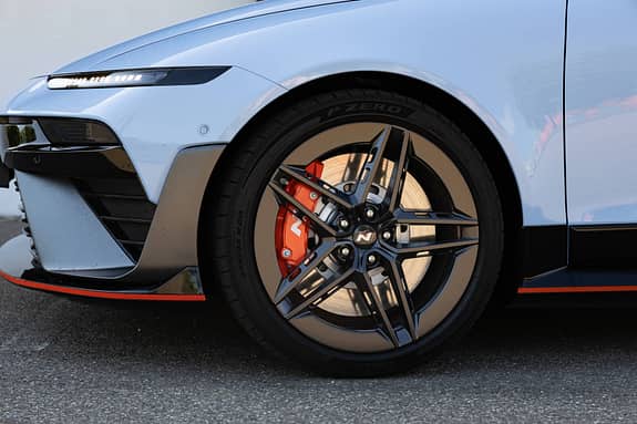 Detailaufnahme des Vorderrads und der Frontpartie eines Hyundai Ioniq 6N AWD. Sichtbar sind die sportliche Felge, die rote Bremssattel mit N-Logo und die Frontscheinwerfer.