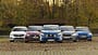 Fünf Kleinwagen-Modelle (Mitsubishi Colt, Dacia Sandero, Opel Corsa, Skoda Fabia, Hyundai i20) nebeneinander auf einem Parkplatz in herbstlicher Umgebung, frontal fotografiert.