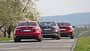 Drei Limousinen, Alfa Romeo Giulia 2.2 Diesel Q4, BMW 320d und Mercedes C 220d, fahren auf einer Landstraße. Die Fahrzeuge sind von hinten zu sehen, umgeben von blühenden Bäumen und einer hügeligen Landschaft.