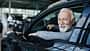07/2026, Senior im Auto Ein älterer Mann mit weißem Bart am Steuer eines Pkw schaut lächelnd aus einem geöffneten Autofenster
