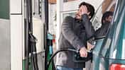 Young man refueling his vehicle while looking worried at the high gas prices.
