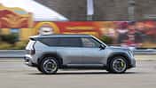 Kia EV9 GT (6 Sitzer) fährt in der Stadt, Seitenansicht, silberner Elektro-SUV vor urbanem Hintergrund.