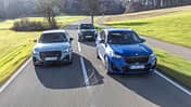 Drei Kompakt-SUVs (Audi SQ2, BMW X1 M35i, Mini JCW Countryman) fahren nebeneinander auf einer Landstraße.