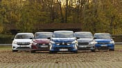 Fünf Kleinwagen-Modelle (Mitsubishi Colt, Dacia Sandero, Opel Corsa, Skoda Fabia, Hyundai i20) nebeneinander auf einem Parkplatz in herbstlicher Umgebung, frontal fotografiert.