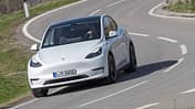 Tesla Model Y in weiß auf einer kurvigen Landstraße während eines Dauertests, frontal fotografiert.
