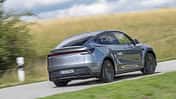Tesla Model Y AWD auf Landstraße, Heckansicht, silberfarbenes Elektro-SUV, ländliche Umgebung.