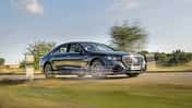 Mercedes S580 Limousine fährt auf einer Landstraße, dynamische Seitenansicht, sommerliche Landschaft.