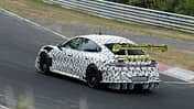 Erlkönig Xiaomi SU7 Ultra Extreme auf dem Nürburgring mit starker schwarz-weiß Tarnung sowie einem gelb abgesetzten großen Heckspoiler.